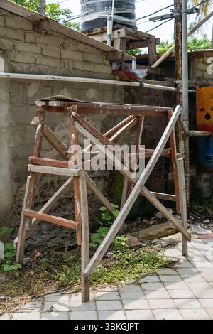 Wooden ladder leaning against a brick wall. The ladder is old and rusted. The scene is somewhat abandoned and gives off a feeling of neglect Stock Photo