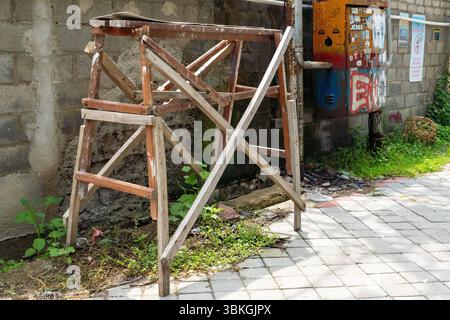 Wooden ladder leaning against a brick wall. The ladder is old and rusted. The scene is somewhat abandoned and gives off a feeling of neglect Stock Photo