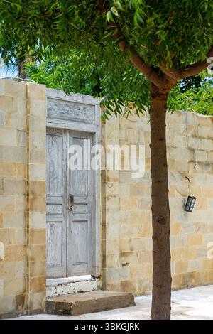 White door with a wooden frame is in front of a brick wall. The door is open and the wall is covered in bricks Stock Photo