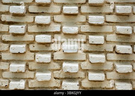 The wall is made of white bricks and has a pattern. The bricks are arranged in a way that creates a unique and interesting design Stock Photo