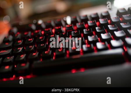 Close up of illuminated keyboard highlighting gaming and technology themes, featuring red backlit keys and a sleek black design Stock Photo
