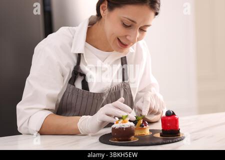 Confectioner decorating tart with mint at table Stock Photo