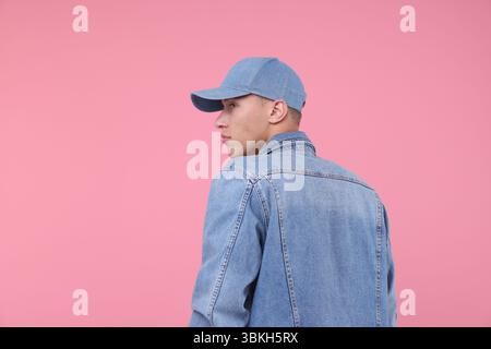 Young man wearing stylish denim baseball hat on pink background, space for text Stock Photo
