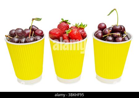 Three vibrant yellow paper cups are filled to the brim with fresh, ripe berries. Two cups contain dark red cherries, some with their green stems still Stock Photo