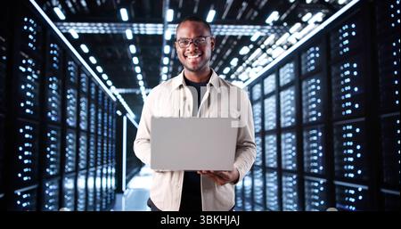 Smiling IT Technician Setting Up Artificial Intelligence System In Server Room. Stock Photo