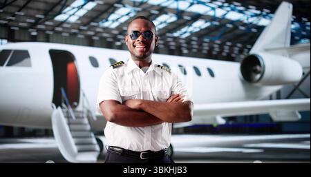 Smiling African American Man In Aviation Uniform Boarding Private Jet. Stock Photo