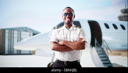 Young African American Man Smiles As Private Jet Pilot At Airport. Stock Photo