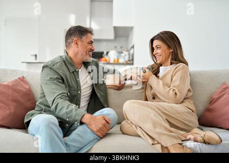 Happy middle aged mature couple talking relaxing on couch at home. Stock Photo