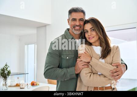 Happy middle aged mature couple hugging standing at home. Portrait. Stock Photo