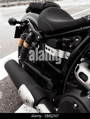 The image shows a close-up view of a black motorcycle parked on the side of a road, highlighting its sleek design and metallic components. The bike ap Stock Photo