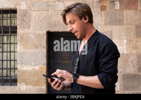 emotional man with earphone looking at phone Stock Photo