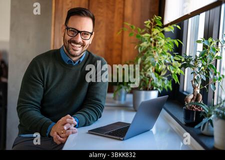 Satisfied man using laptop computer for electronic banking, making reservation, online shopping Stock Photo