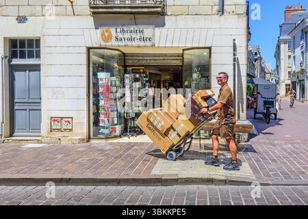 UPS (United Parcel Service) courier delivering a stack of boxed goods on a 2-wheel hand cart to a shop in Tours, central France. Stock Photo