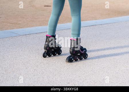 Close-up of inline skates worn by a woman standing on smooth pavement, preparing to skate Stock Photo