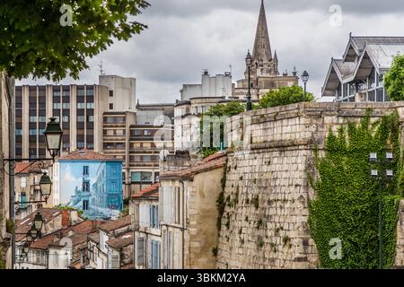 The mural "La Fille des remparts" (The Girl of the Ramparts) by Max Cabanes glows in shades of blue above the rooftops of the city, Rue Léonard Jarraud, Angoulême, Nouvelle-Aquitaine, France. In it, a woman leans against a painted city wall that continues into the original city wall. The blue tones recall Béziers in the south of France, the comic artist's home town. The 120-square-metre trompe-l'œil was created in 2004. Cabanes won the Grand Prix of the city's International Comics Festival in 1990. Old and modern buildings mix in the townscape. The ivy-covered city wall runs through the foregr Stock Photo