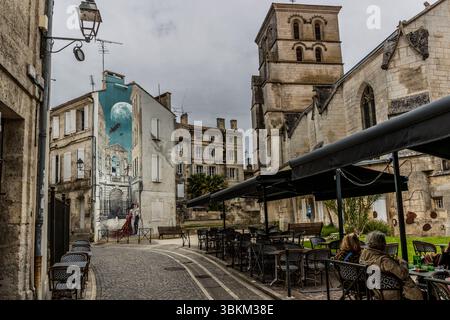 A mural depicts a scene with a couple, an aeroplane and a moon set against the backdrop of historic architecture. It is an example of street art that beautifies the city and reflects the history and culture of the region. Angoulême is recognized as a UNESCO Creative City in the category of literature since 2019. Rue Sainte-Marie, Angoulême, Nouvelle-Aquitaine, France Stock Photo