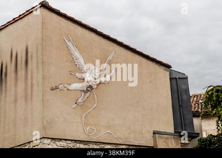 A mural depicts an angel ascending to heaven. The artwork can be seen on the façade of a building and adds an artistic touch to the surroundings. Angoulême is recognized as a UNESCO Creative City in the category of literature since 2019. Rue Saint-André, Angoulême, Nouvelle-Aquitaine, France Stock Photo
