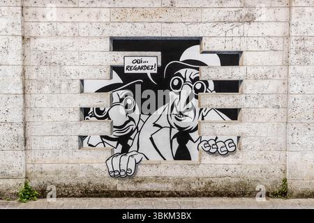 The mural depicts comic book characters with speech bubbles that appear to be bursting out of the wall. "Do you see anything? Yes, look. It's exactly what I feared. What, another underworld? Worse than that. It's reality." From the series "Réalité, Sortie de Secours" (Reality, Emergency Exit), designed by Marc-Antoine Mathieu and produced by Cité de la Création. Angoulême is recognized as a UNESCO Creative City in the category of literature since 2019. Rue de Beaulieu, Angoulême, Nouvelle-Aquitaine, France Stock Photo