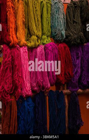The image showcases a stunning display of colorful yarns neatly arranged on a wooden rack. The vibrant colors range from bright pinks and purples to d Stock Photo