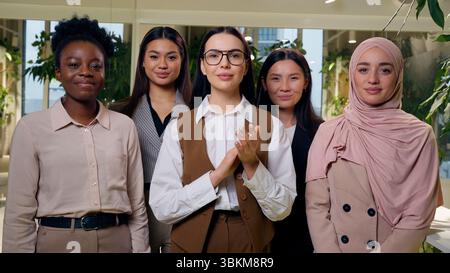 Happy satisfied multiethnic women females diverse group five girls coworkers businesswomen business team nodding head clapping hands applauding Stock Photo