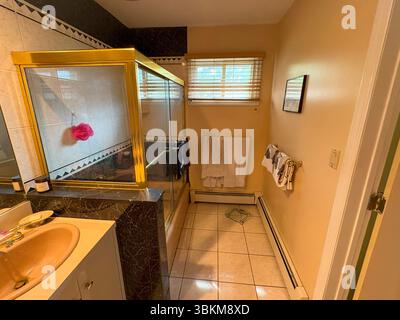 A well-kept bathroom featuring gold fixtures and neatly arranged towels. Stock Photo