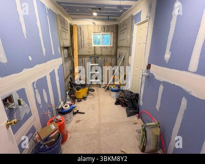Babylon, New York, USA - 8 June 2025: Construction work is ongoing in a small room with tools and materials scattered around. Stock Photo