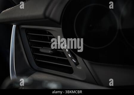 Close-up of a sleek car interior featuring an air vent and control knobs, showcasing modern automotive design and functionality. Stock Photo
