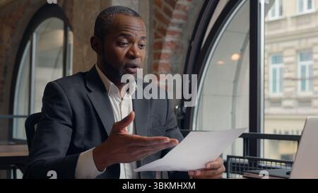 Talking African American man business employer company CEO presentation virtual negotiation talk laptop computer video conference call showing stats Stock Photo