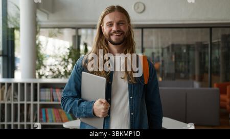 Caucasian student guy man male posing in university college academy hall corridor holding laptop smiling happy looking at camera studying learning Stock Photo