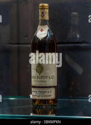 Old cognac bottle from the house of Baron Otard with the symbol of a red cross. Cognac was sold as a medicine at the time of Prohibition. Sightseeing tour with tasting at the Château de Cognac. Rue François 1er, Cognac, Nouvelle-Aquitaine, France Stock Photo