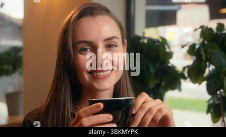 Happy smiling relaxed Caucasian woman girl female business businesswoman lady indoors in cafe in cafeteria restaurant drinking aroma coffee tea drink Stock Photo