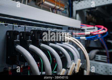 Bunch of wires are connected to a box. The wires are white and blue. The box is gray Stock Photo