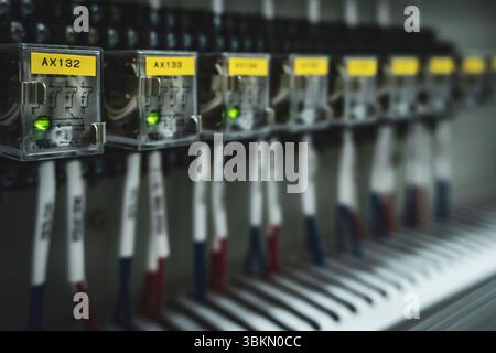 Row of switches with yellow labels on them. The switches are labeled with numbers. The switches are all lit up Stock Photo