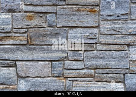 A detailed close-up of a gray stone brick wall with a stacked layout. The image features natural textures, rough surfaces, and subtle color variations Stock Photo