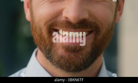 Close up cropped view Caucasian half face mouth lips smiling toothy unrecognizable European bristle bearded man smile white tooth healthy dental oral Stock Photo