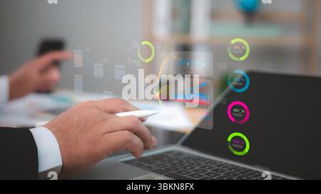 Business professional analyzing holographic data visualizations, charts, and metrics above a laptop. Business intelligence, financial analysis, digita Stock Photo