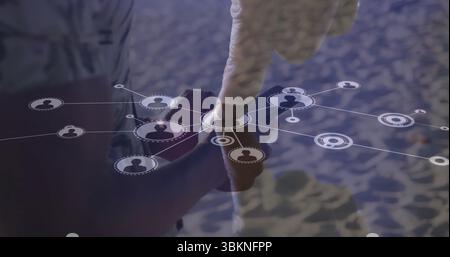 Holding two men's hands tapping smartphone screen on sandy shoreline, with digital network overlays Stock Photo