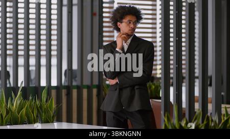 Pensive thoughtful puzzled thinking African American businessman employer developer employer business man male guy walk going walking in office ponder Stock Photo