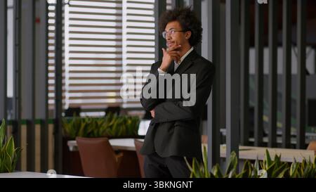 Pensive thoughtful puzzled thinking African American businessman employer developer employer business man male guy walk going walking in office ponder Stock Photo