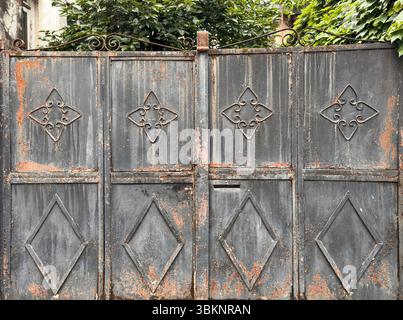Wrought iron gate with geometric and floral patterns, aged metal surface with rust and texture. Useful as background, texture or design element Stock Photo