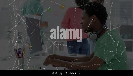 Typing software developer wearing green tee on computer at desk with whiteboard notes, copy space Stock Photo