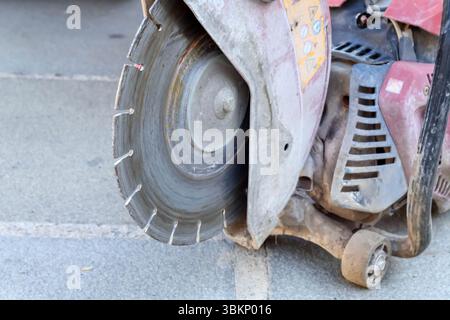 a construction tool, most likely a concrete or asphalt cutter, with a large metal blade and visible signs of wear. Stock Photo
