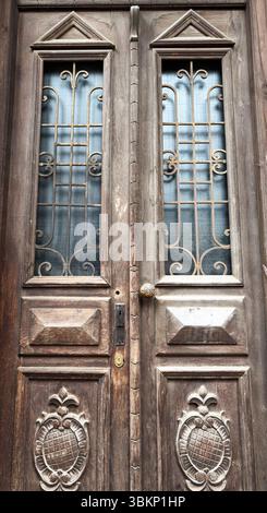 Close-up of a symmetrical vintage wooden door with carved panels and decorative iron grilles. Useful for backgrounds, or architecture themes. Stock Photo