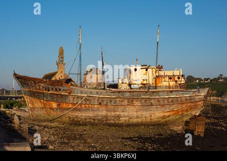 Old weathered and decaying wooden fishing boats at the historic boat cemetery in Camaret-sur-Mer, Brittany, France, seen at dusk under a clear sky. Stock Photo