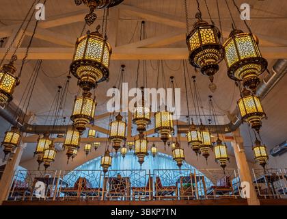 Exotic Atmosphere: stunning installation of ornate Moroccan lanterns illuminates a cozy restaurant interior.Authentic Middle Eastern Ambiance: Ornate Stock Photo