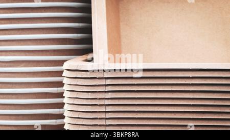 A stack of brown recycled cardboard boxes with a white box in the middle. The boxes are stacked on top of each other Stock Photo
