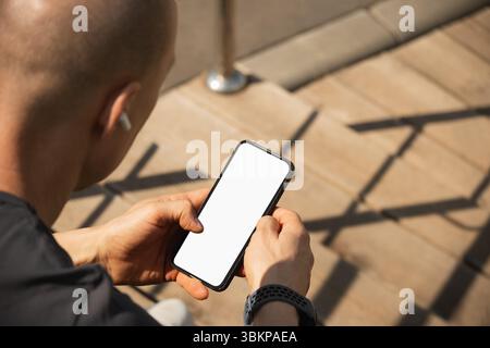 Athlete sitting on stairs and checking apps after training. Relax after training. Man listens to music. Summer season. Close up. Stock Photo