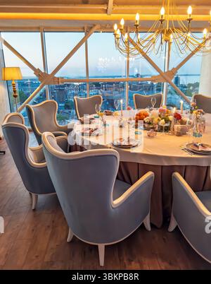 Elegant restaurant table setting with a panoramic view of the city at dusk.Beautifully served table for a celebration in a modern restaurant interior Stock Photo
