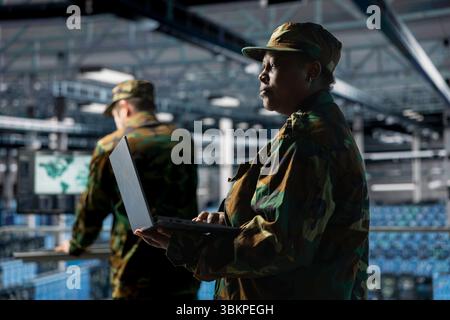 Soldier in server hub updating secure firmware on military data center hardware. African american army information technology expert in data center managing defense systems protocols Stock Photo