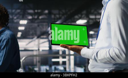 Close up of engineer using green screen mockup tablet in data center to update servers tech, configuring equipment. Server room admin reviewing hardware analytics on chroma key device Stock Photo